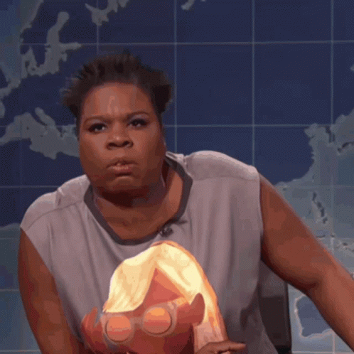 A Woman In A Gray Shirt Holds A Doll In Front Of A Map GIF