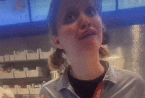 A Woman In A Gray Shirt With A Red Lanyard Around Her Neck Smiles GIF