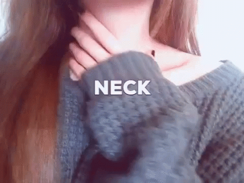 A Woman In A Gray Sweater Is Holding Her Neck . GIF