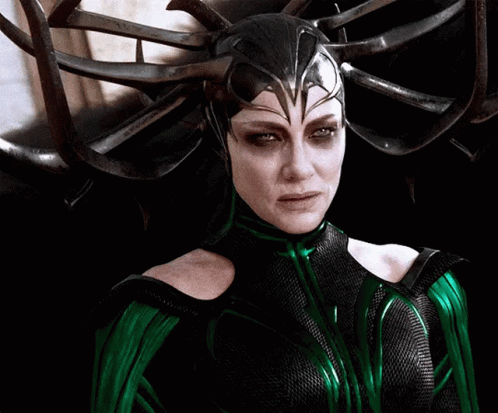 A Woman In A Green And Black Costume With A Helmet On Her Head GIF