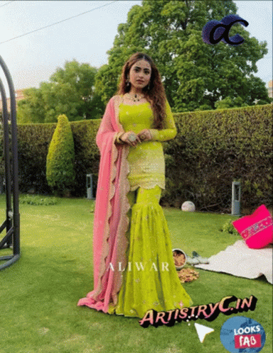 A Woman In A Green And Pink Dress Is Standing On A Lush Green Lawn GIF