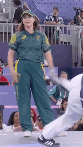 A Woman In A Green And Yellow Uniform Is Standing Next To A Man In A White Uniform . GIF