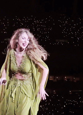 A Woman In A Green Dress Dancing On A Stage GIF