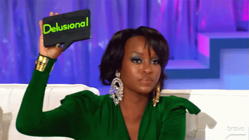 A Woman In A Green Dress Holds Up A Sign That Says Delusional GIF