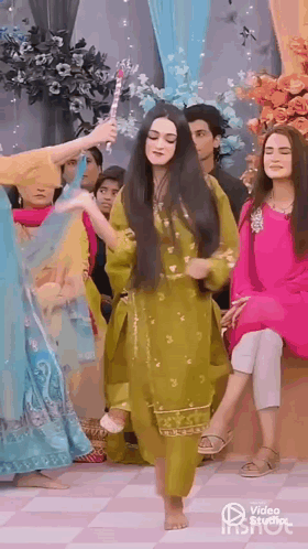 A Woman In A Green Dress Is Dancing Barefoot In Front Of A Group Of People . GIF