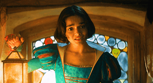 A Woman In A Green Dress Is Holding A Lantern GIF