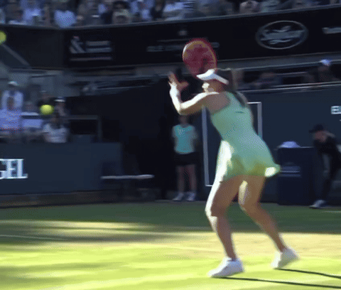 a woman in a green dress is holding a tennis racket on a tennis court