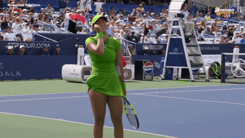 A Woman In A Green Dress Is Holding A Tennis Racquet GIF