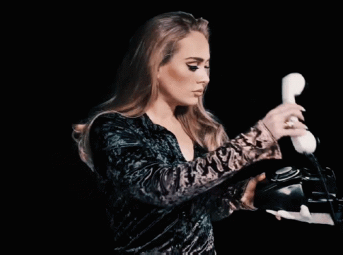 A Woman In A Green Dress Is Holding A White Telephone GIF