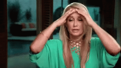 A Woman In A Green Dress Is Holding Her Head In Pain . GIF