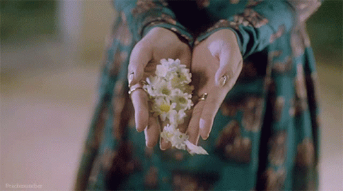A Woman In A Green Dress Is Holding White Flowers GIF