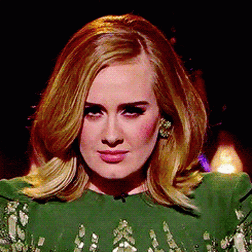A Woman In A Green Dress Is Looking At The Camera GIF