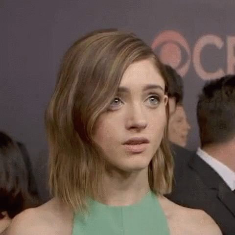 A Woman In A Green Dress Is Making A Funny Face While Standing In A Crowd Of People . GIF