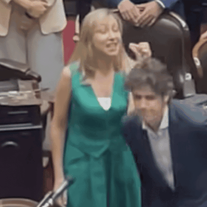 A Woman In A Green Dress Is Posing For A Picture With A Man In A Suit GIF