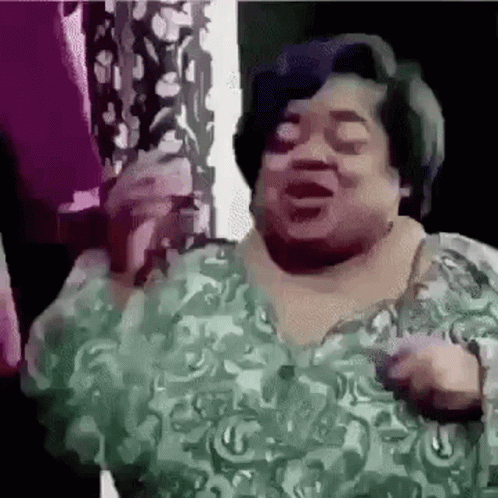 A Woman In A Green Dress Is Singing Into A Microphone And Dancing . GIF