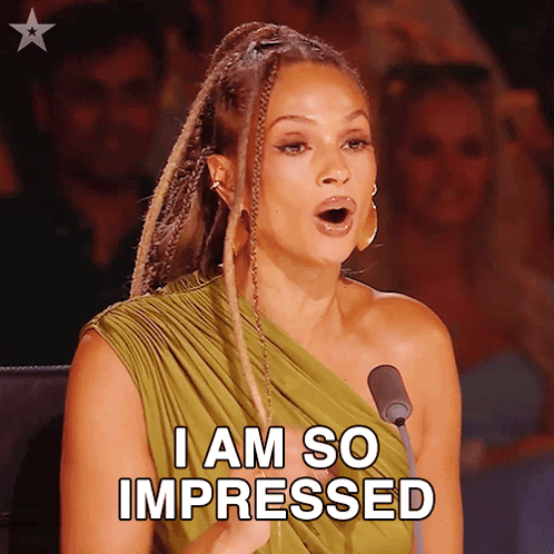 A Woman In A Green Dress Is Speaking Into A Microphone And Says " I Am So Impressed " GIF