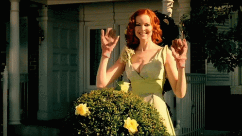 A Woman In A Green Dress Is Standing In Front Of A White House GIF