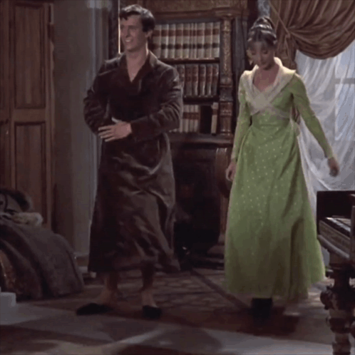 Woman In Green Dress Next To Man In Black Robe GIF
