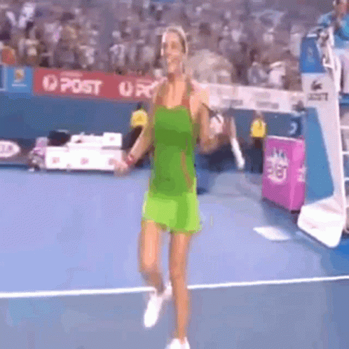 A Woman In A Green Dress Is Walking On A Tennis Court . GIF