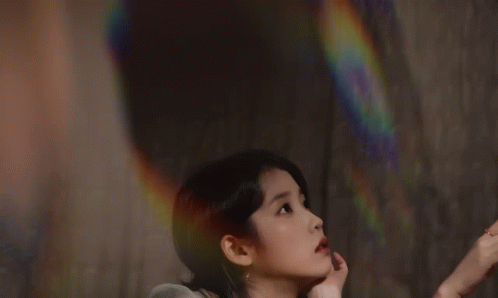 A Woman In A Green Dress Reaches For A Pink Rose GIF
