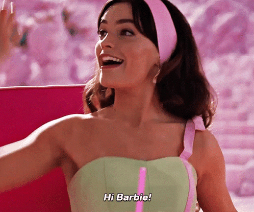 A Woman In A Green Dress Says Hi Barbie In A Pink Headband GIF