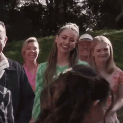 A Woman In A Green Dress Smiles While Standing In A Crowd Of People GIF