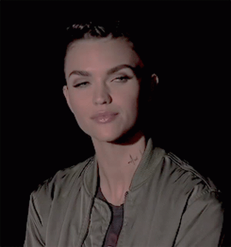 A Woman In A Green Jacket Has A Tattoo On Her Neck GIF