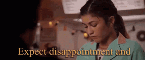 A Woman In A Green Jacket Is Looking Down And The Words `` Expect Disappointment And '' Are Behind Her . GIF