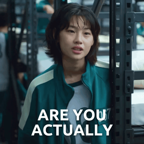 A Woman In A Green Jacket Is Standing Next To A Sign That Says Are You Actually GIF