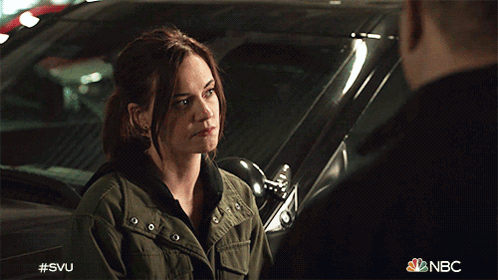 A Woman In A Green Jacket Is Talking To A Man In A Black Shirt In Front Of A Car That Says Nbc GIF
