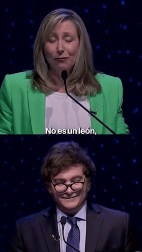 A Woman In A Green Jacket Says No Es Un Leon Next To A Man GIF