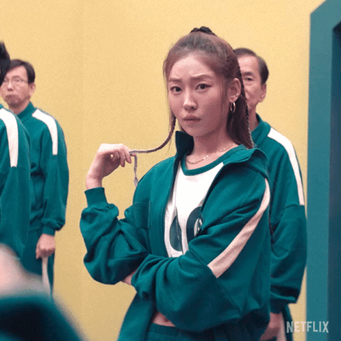 A Woman In A Green Jacket With The Letter O On The Front GIF