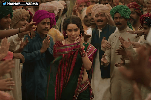 A Woman In A Green Saree Is Surrounded By A Crowd Of People With The Words Pranay Varma Above Her GIF