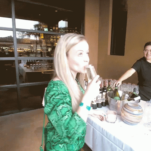 A Woman In A Green Shirt Drinks From A Glass GIF