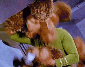 a woman in a green shirt is holding a stuffed animal and kissing it .
