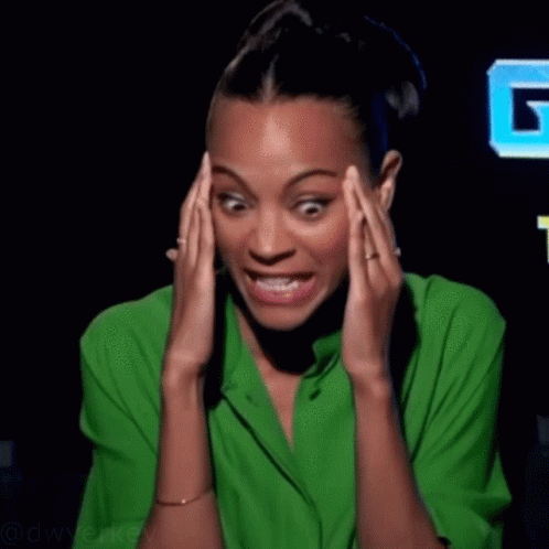A Woman In A Green Shirt Is Holding Her Head In Pain GIF