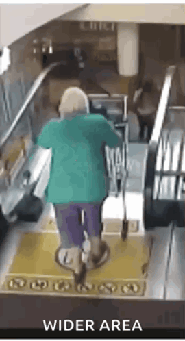 a woman in a green shirt is riding an escalator in a wider area