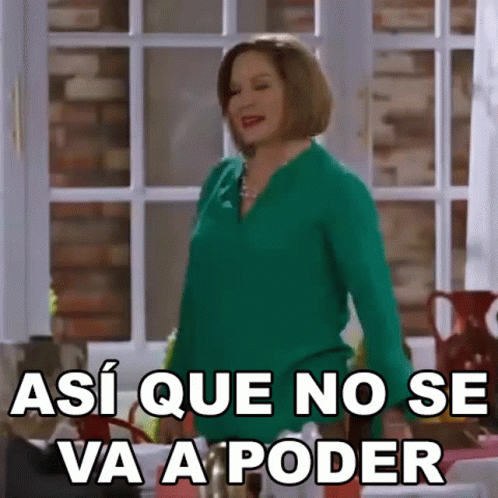 A Woman In A Green Shirt Is Standing In Front Of A Window And Making A Funny Face . GIF