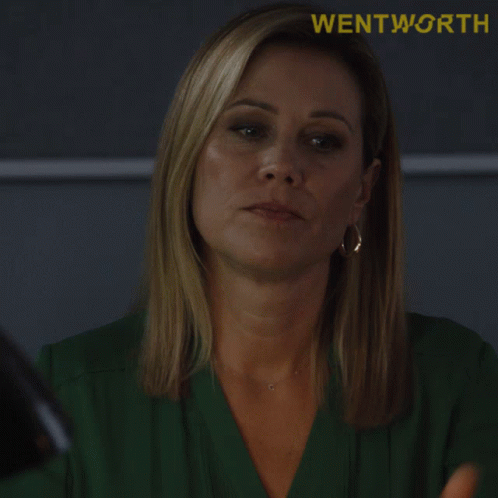 A Woman In A Green Shirt With The Words Take A Seat Written Below Her GIF