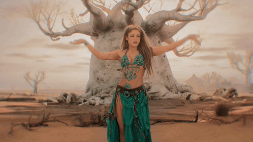 a woman in a green skirt is dancing in front of a tree