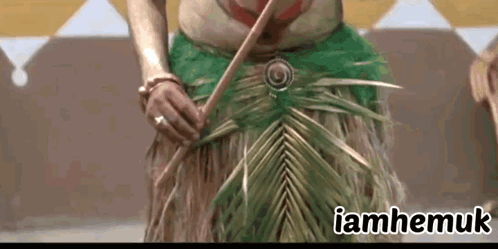 A Woman In A Green Skirt Is Holding A Palm Leaf And The Words Iamhemuk Are Above Her GIF
