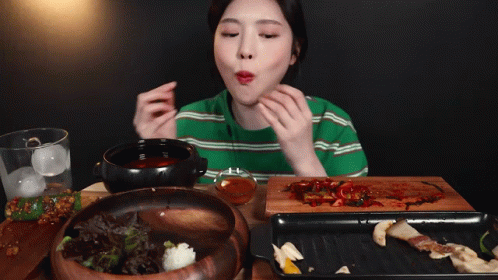 A Woman In A Green Striped Shirt Is Eating A Bowl Of Food GIF