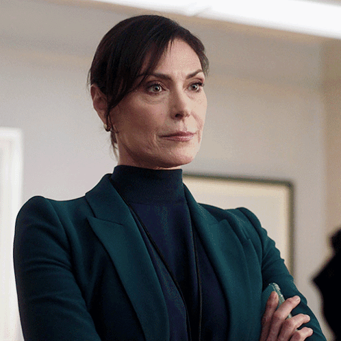 A Woman In A Green Suit And Black Turtleneck GIF