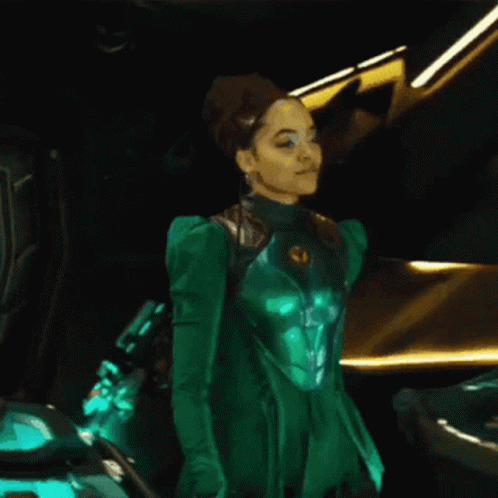 A Woman In A Green Suit Is Standing Next To A Car GIF