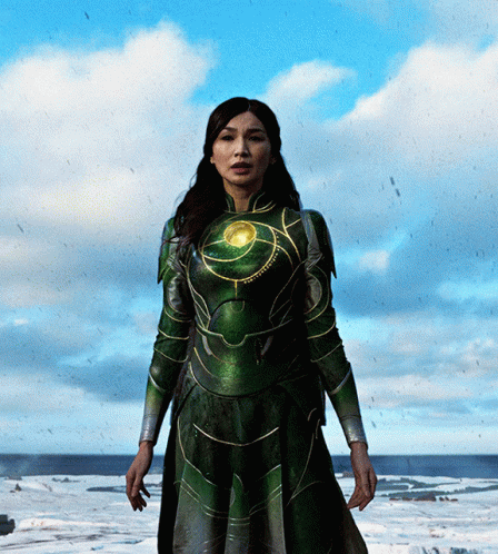 A Woman In A Green Superhero Costume Stands In The Snow GIF