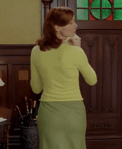 A Woman In A Green Sweater And Green Skirt GIF