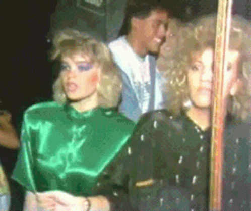 a woman in a green top stands next to another woman in a black top
