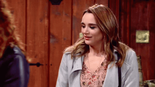 A Woman In A Grey Coat Is Talking To Another Woman GIF