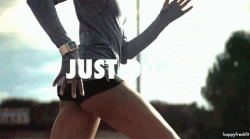 A Woman In A Grey Shirt And Black Shorts Is Dancing With The Words Just Do It Above Her GIF