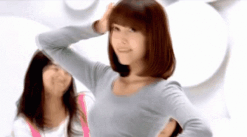 A Woman In A Grey Shirt Is Standing Next To Another Woman In A Pink Shirt GIF
